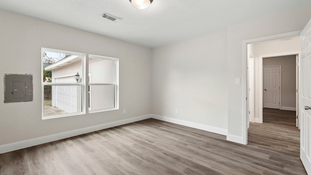 empty room featuring electric panel and wood-type flooring