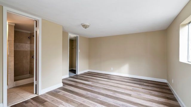 unfurnished bedroom with hardwood / wood-style floors and connected bathroom