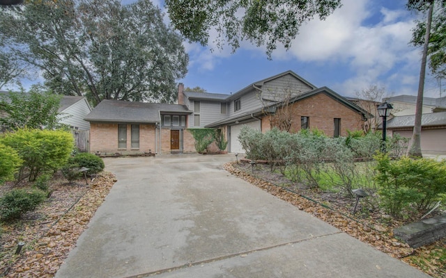 view of front of home with concrete driveway, brick siding, a chimney, and an attached garage