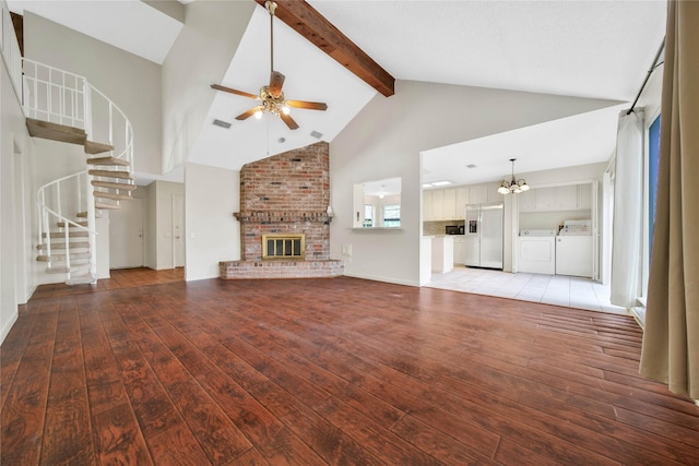 unfurnished living room with ceiling fan with notable chandelier, a fireplace, high vaulted ceiling, independent washer and dryer, and hardwood / wood-style flooring