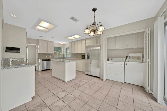 kitchen featuring separate washer and dryer, pendant lighting, appliances with stainless steel finishes, a chandelier, and light tile patterned floors