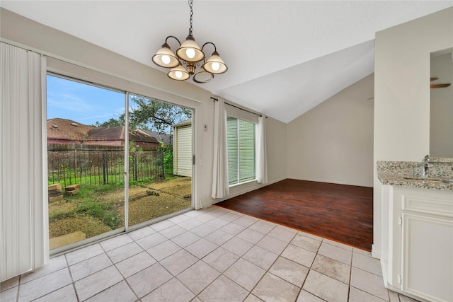 unfurnished dining area with light tile patterned floors, vaulted ceiling, sink, and an inviting chandelier