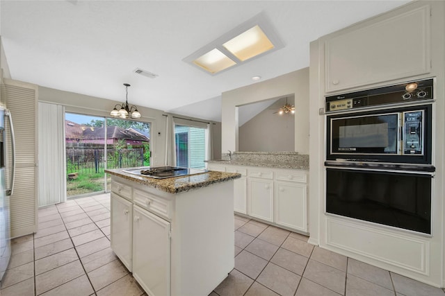 kitchen with black appliances, light tile patterned floors, white cabinetry, and a center island