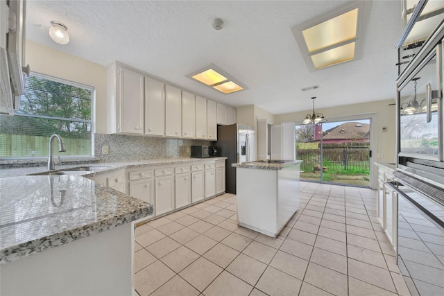 kitchen with light tile patterned flooring, sink, white cabinets, and a center island