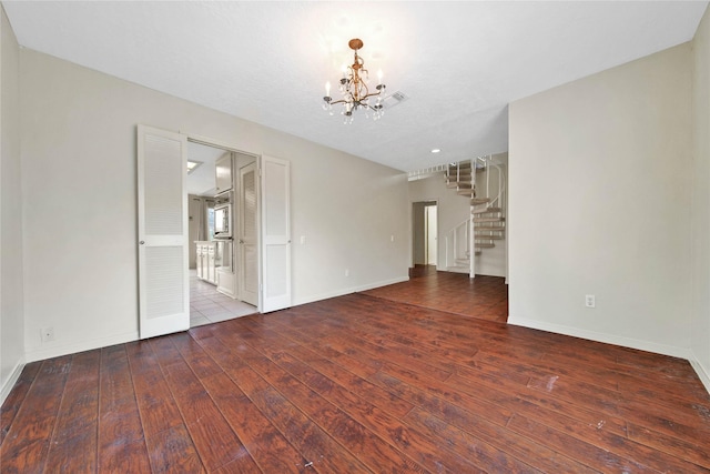 spare room featuring a notable chandelier and hardwood / wood-style floors