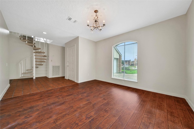 unfurnished living room with a textured ceiling, dark hardwood / wood-style floors, and a notable chandelier