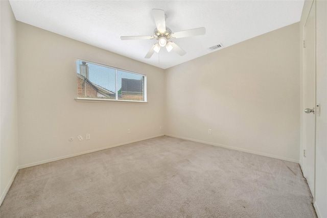 spare room with ceiling fan and light carpet