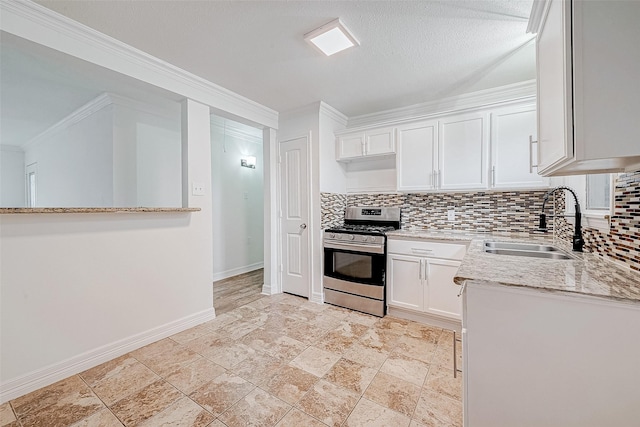 kitchen with sink, white cabinets, stainless steel gas range oven, backsplash, and light stone countertops