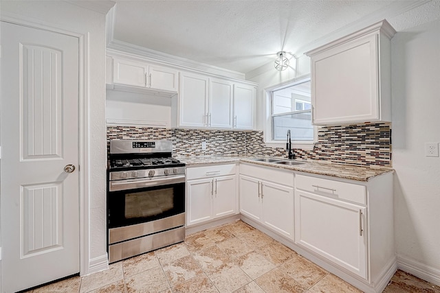 kitchen featuring white cabinets, stainless steel gas stove, backsplash, and sink