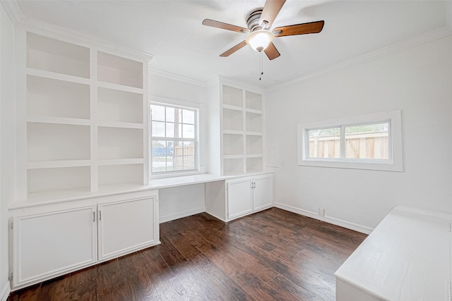 unfurnished office with built in desk, ceiling fan, plenty of natural light, and crown molding