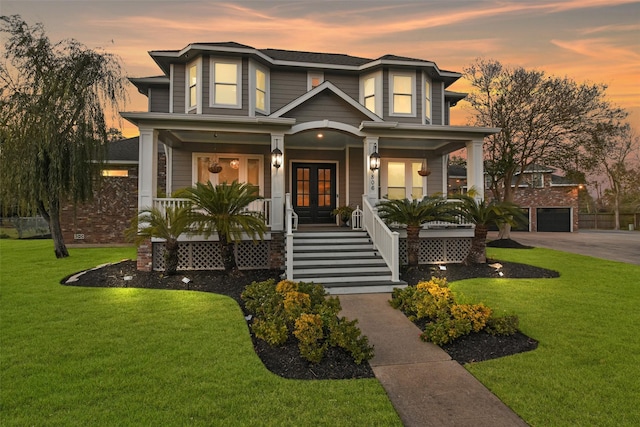 view of front facade featuring french doors, a porch, a yard, and a garage