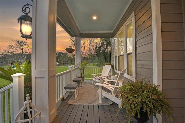 deck at dusk featuring covered porch