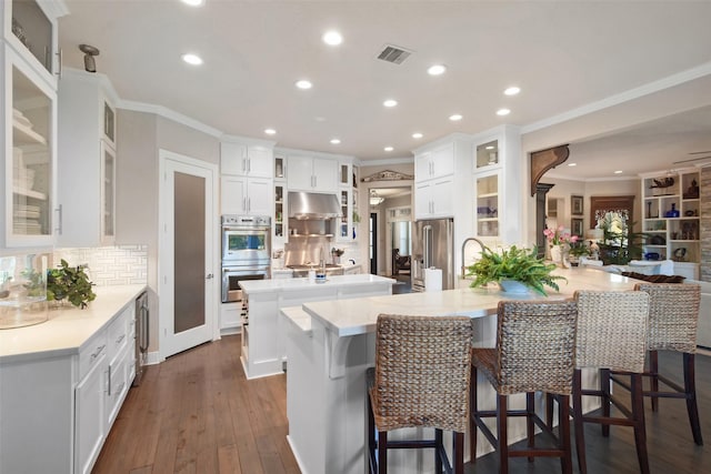 kitchen with white cabinetry, dark hardwood / wood-style flooring, stainless steel appliances, kitchen peninsula, and a breakfast bar area