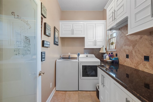 washroom with light tile patterned floors, washer and clothes dryer, and cabinets