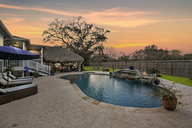 pool at dusk with a gazebo and a patio area