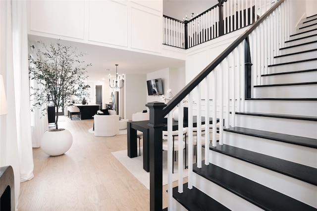 staircase featuring a high ceiling, a chandelier, and hardwood / wood-style flooring