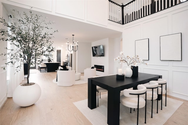 dining space featuring a towering ceiling, a chandelier, and light hardwood / wood-style flooring