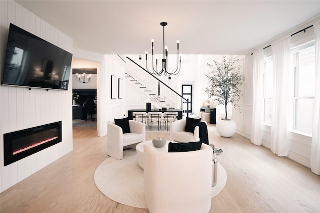 living room featuring a large fireplace, light hardwood / wood-style floors, and a notable chandelier