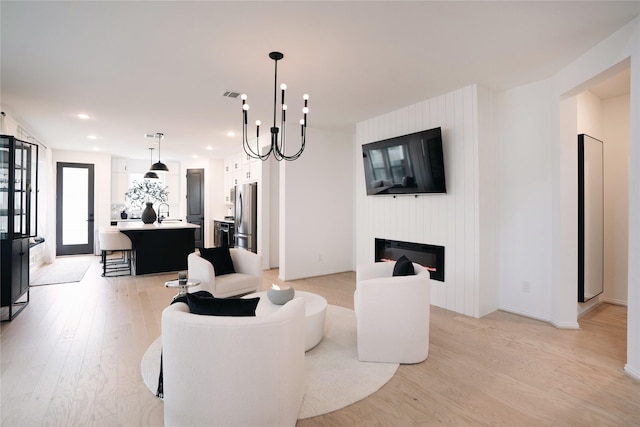 living room with a fireplace, an inviting chandelier, and light wood-type flooring