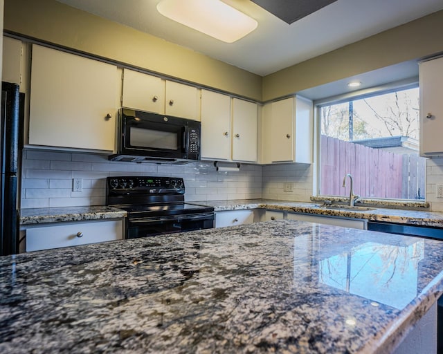 kitchen with black appliances, backsplash, white cabinets, dark stone countertops, and sink