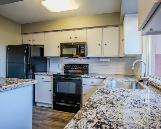 kitchen featuring light stone countertops, white cabinetry, black appliances, and sink