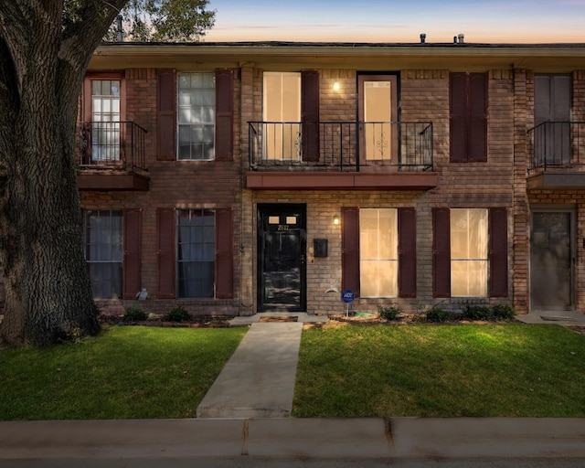 view of front facade with a balcony and a yard