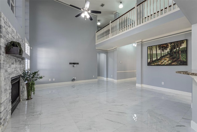 unfurnished living room with a high ceiling, a fireplace, and ceiling fan