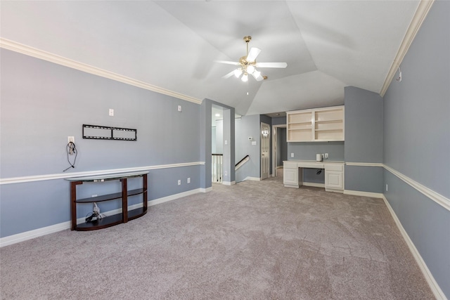 carpeted living room with built in desk, vaulted ceiling, ornamental molding, and ceiling fan