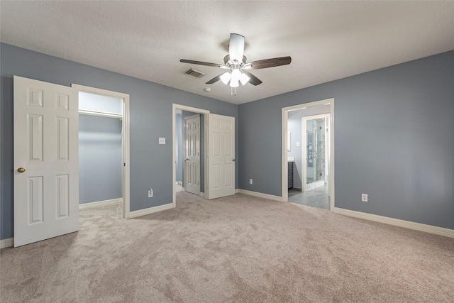 unfurnished bedroom featuring a walk in closet, light colored carpet, ceiling fan, and a closet