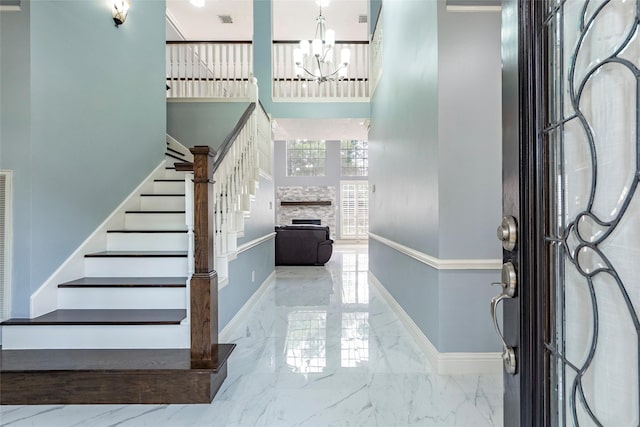 foyer entrance featuring a notable chandelier and a stone fireplace