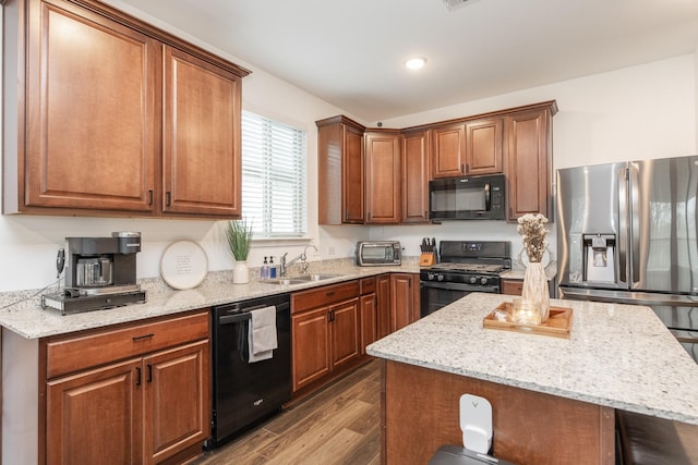 kitchen with hardwood / wood-style floors, a center island, black appliances, and sink