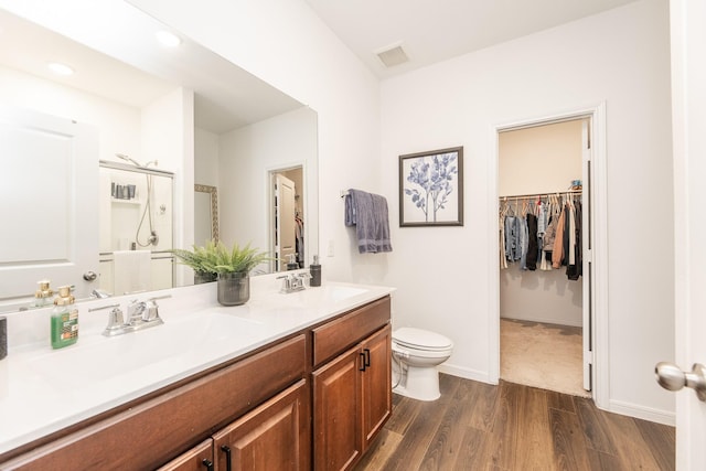 bathroom featuring toilet, vanity, a shower with shower door, and hardwood / wood-style floors