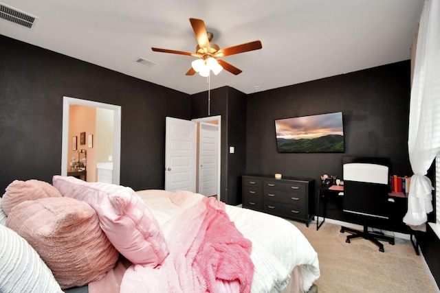 bedroom with light colored carpet, ceiling fan, and connected bathroom