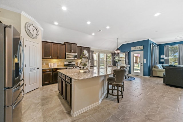 kitchen featuring stainless steel appliances, a kitchen island with sink, vaulted ceiling, and hanging light fixtures