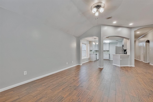 unfurnished living room with ceiling fan, hardwood / wood-style floors, and lofted ceiling