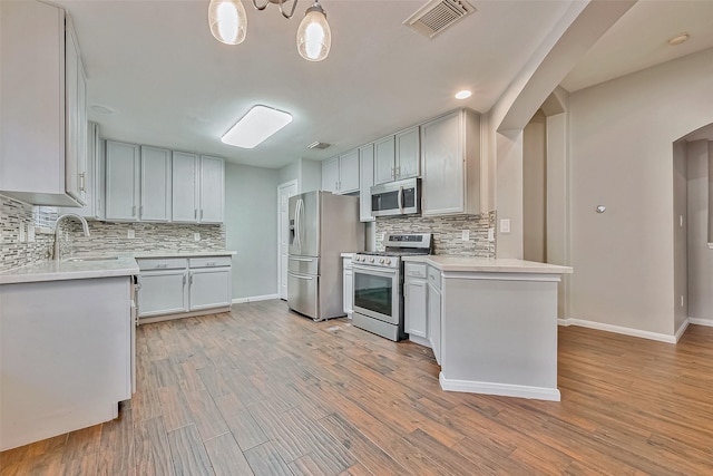 kitchen with white cabinets, decorative light fixtures, stainless steel appliances, tasteful backsplash, and sink