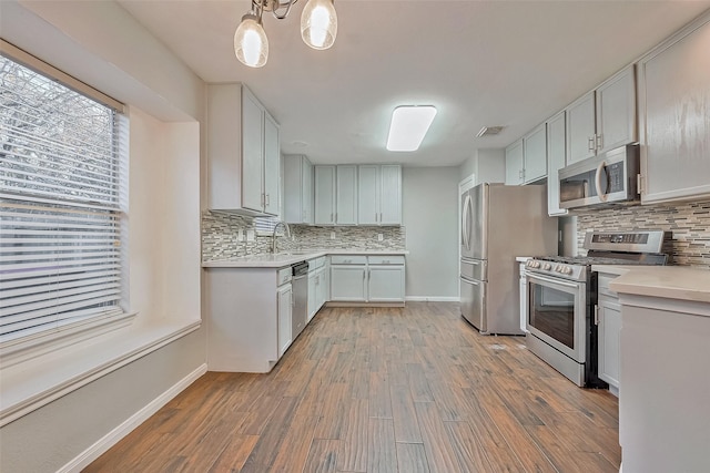 kitchen with stainless steel appliances, white cabinetry, hanging light fixtures, and decorative backsplash