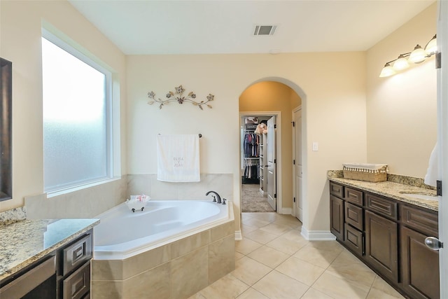 bathroom featuring tiled tub, tile patterned floors, and vanity