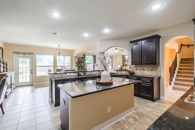 kitchen featuring kitchen peninsula, light tile patterned floors, ceiling fan, pendant lighting, and sink