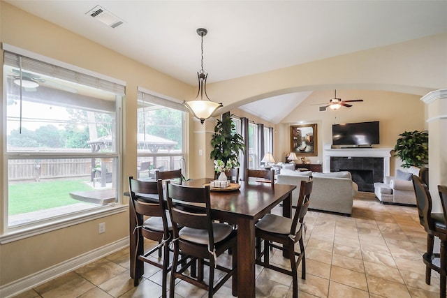 tiled dining space featuring lofted ceiling, a tiled fireplace, and ceiling fan