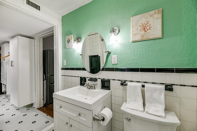 bathroom with tile walls, tile patterned floors, vanity, and toilet