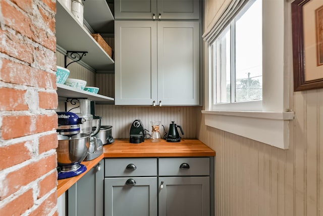 bar with wooden counters, wood walls, and gray cabinets