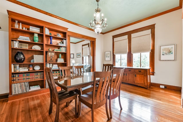 dining space with an inviting chandelier, crown molding, and light hardwood / wood-style flooring