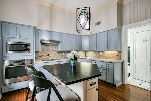 kitchen featuring appliances with stainless steel finishes, tasteful backsplash, a towering ceiling, and a kitchen island