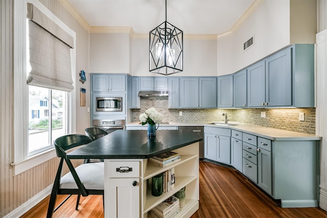 kitchen with pendant lighting, a center island, a high ceiling, appliances with stainless steel finishes, and sink