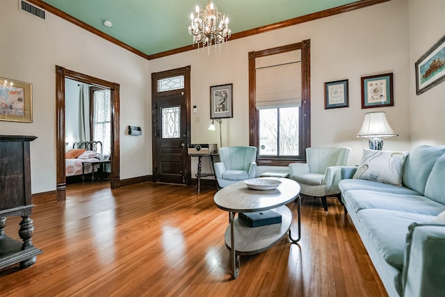 living room featuring a chandelier, hardwood / wood-style floors, and crown molding