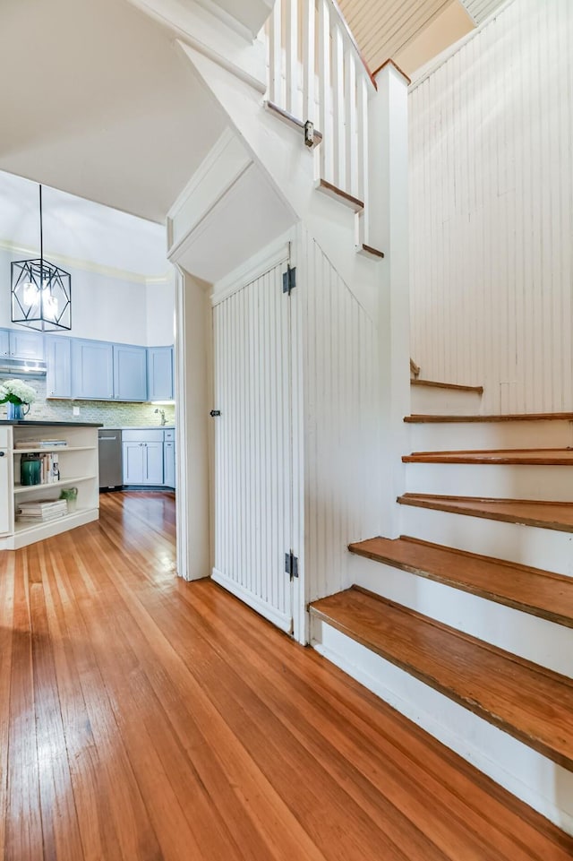 stairs with hardwood / wood-style flooring and a notable chandelier