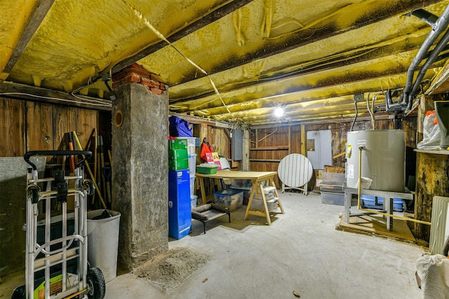 basement featuring electric panel and water heater