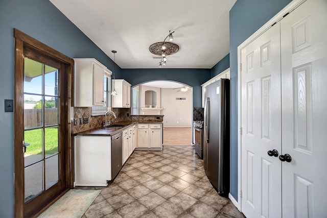 kitchen featuring hanging light fixtures, tasteful backsplash, white cabinets, appliances with stainless steel finishes, and sink