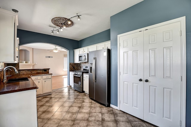 kitchen featuring stainless steel appliances, sink, white cabinetry, kitchen peninsula, and backsplash